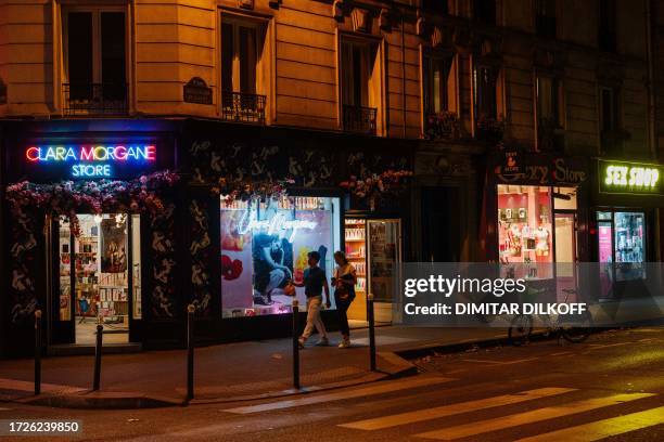 Passerby walk past a sex shops near Place Pigalle at night in Paris on October 13, 2023.