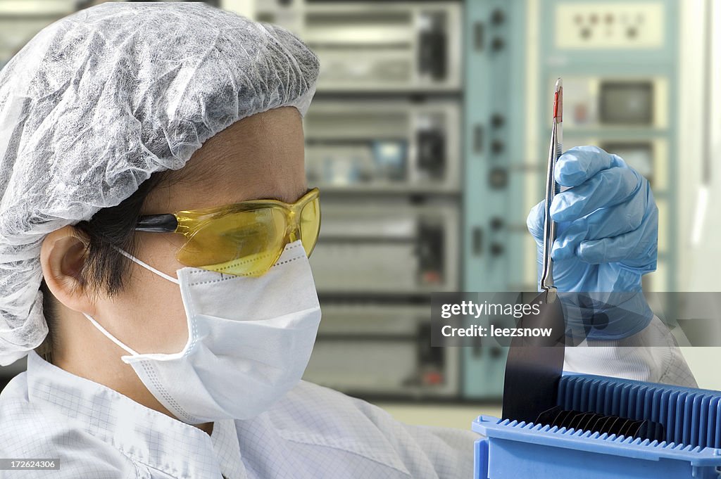 Female Lab Technician Inspecting A Silicon Wafer