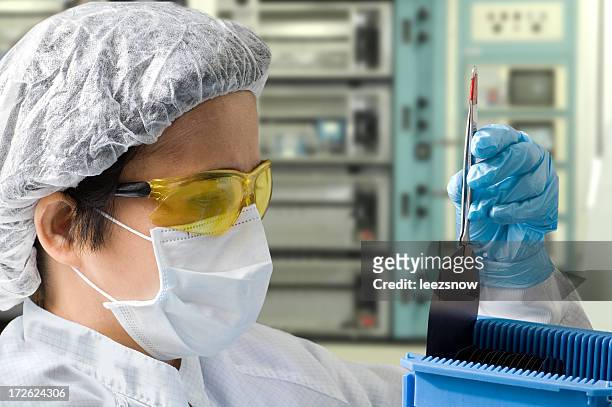 female lab technician inspecting a silicon wafer - computer wafer stock pictures, royalty-free photos & images