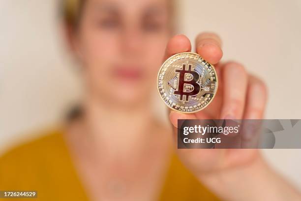 Close up view of woman holding Bitcoin cryptocurrency coin in her hand.