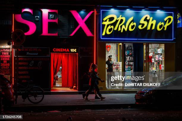 Passerby walk past a sex shops near Place Pigalle at night in Paris on October 13, 2023.