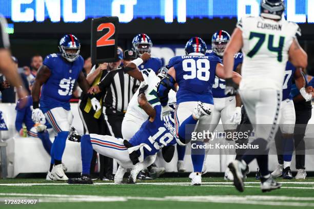 Isaiah Simmons of the New York Giants tackles Geno Smith of the Seattle Seahawks out of bounds during an NFL football game at MetLife Stadium on...