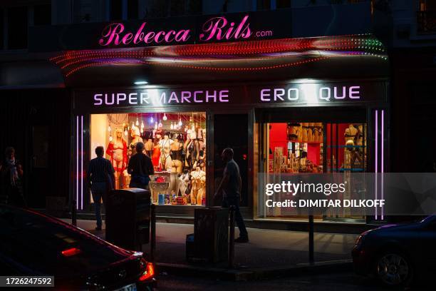 Passerby look at window of a sex shop near Place Pigalle at night in Paris on October 13, 2023.