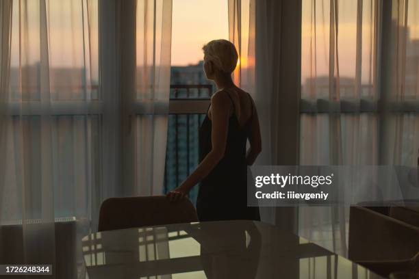 woman looking out the window. morning - smart city stockfoto's en -beelden