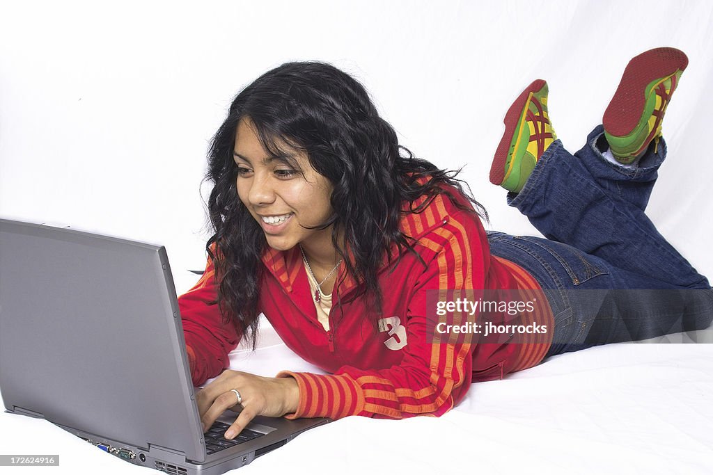 Adolescente ragazza in posizione prona con il suo computer portatile