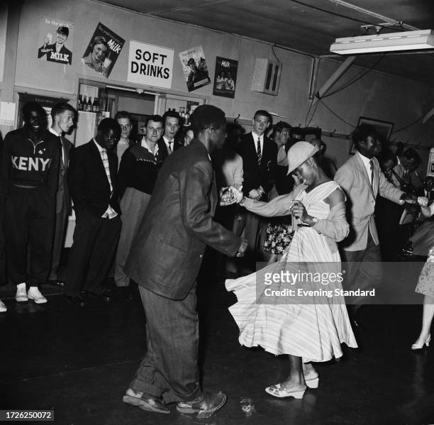 Elizabeth Bright from Sierra Leone and L Richard, athletes competing in the British Empire and Commonwealth Games, dance a jive while being watched...