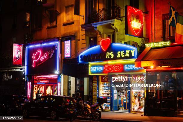 Passerby walks by sex shops near Place Pigalle at night in Paris on October 10, 2023.