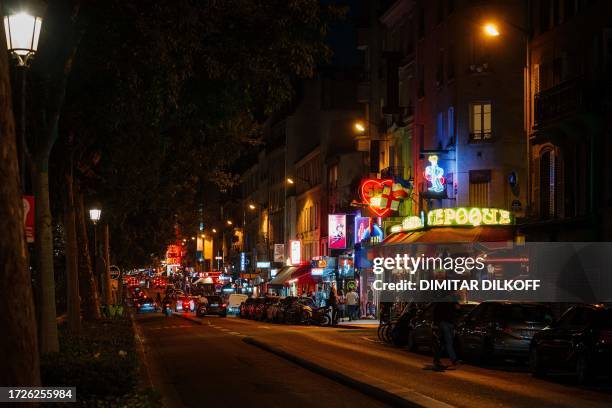 Passersby walk by sex shops near Place Pigalle at night in Paris on October 13, 2023.