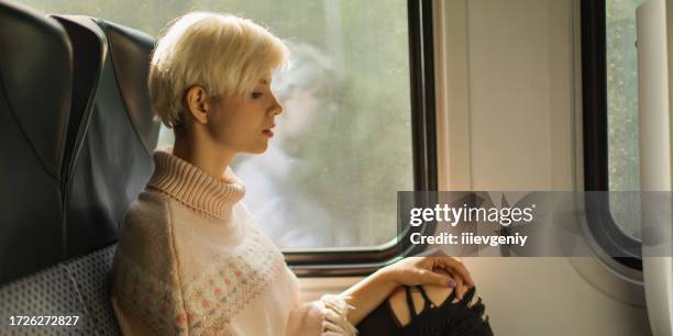 blonde woman traveling on train - woman blond looking left window stockfoto's en -beelden