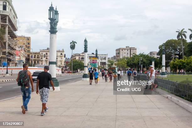 Havana, Cuba, Cuban people and their lifestyle as they walk in the wide sidewalk of the Capitolio building.