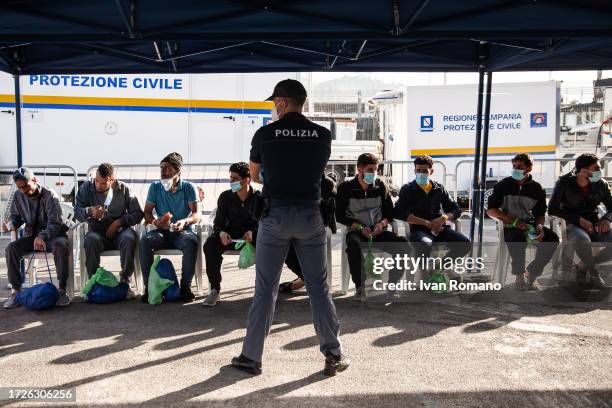 Migrants waiting under a civil protection tent after disembarking from the Geo Barents ship in the port of Salerno on October 09, 2023 in Salerno,...