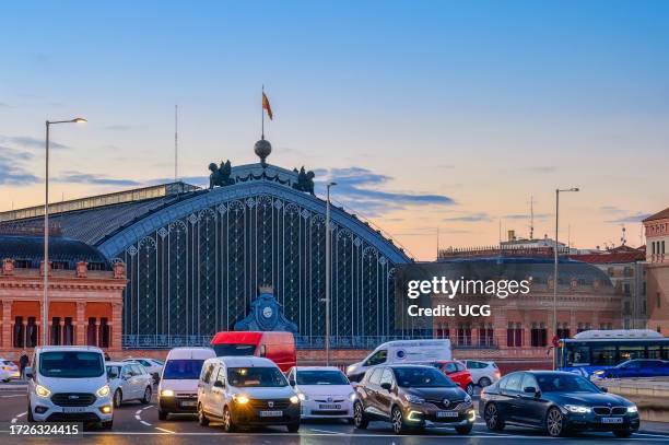 Madrid, Spain, Architectural feature in Atocha Train Station. Morning traffic in front of the transpiration building.