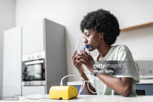young adult black woman suffering asthma using nebuliser - breathing device stock pictures, royalty-free photos & images