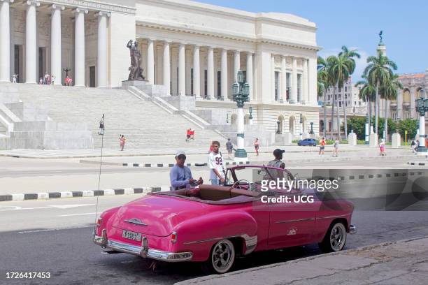 Havana, Cuba, a vintage convertible American car is parked by the Capitolio building. The motor vehicle is used as small private business giving...
