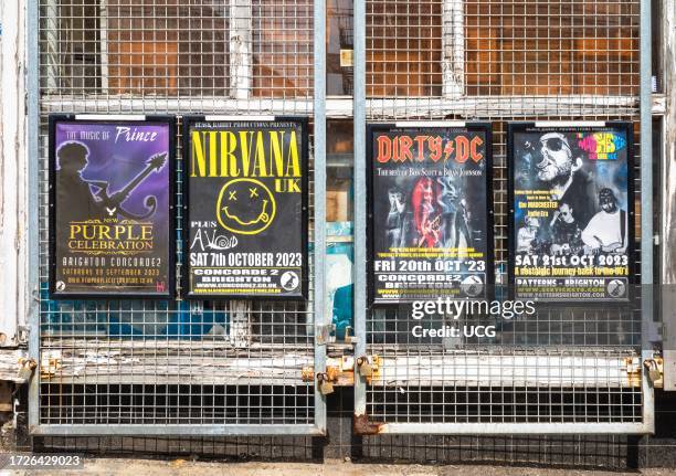 Posters attached to metal grills advertising concerts and gigs by tribute bands in Brighton, East Sussex, UK.