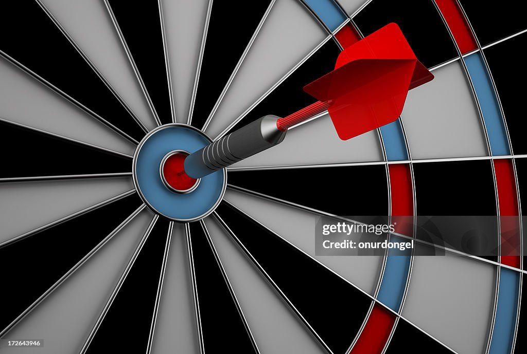 Dart hitting bullseye on dart board