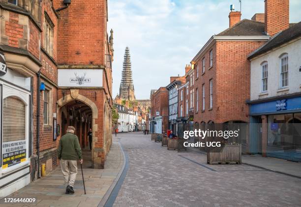 An elderly man walks down Conduit Street at sunrise with a view of Lichfield Cathedral, with its main spire being restored, in the distance in this...