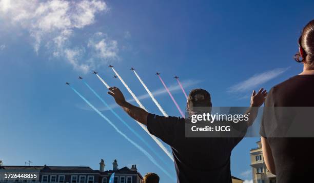 Man on Eastbourne beach stretches out his arms to welcome the world famous RAF display team The Red Arrows as they fly overhead at the annual...