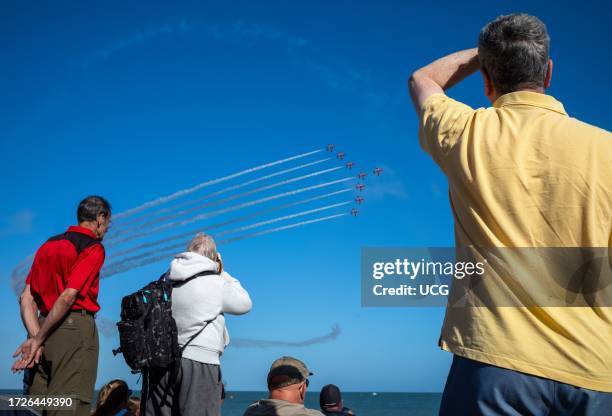 People on Eastbourne beach watch as the world famous RAF display team The Red Arrows fly past the seafront at the annual Eastbourne Airbourne, an...