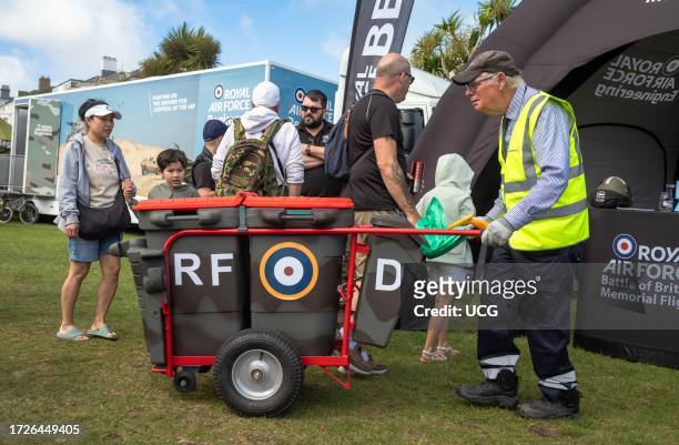 An elderly municipal bin man with his bins painted in the military camouflage colors and with a RAF roundel at the military exhibition alongside the...