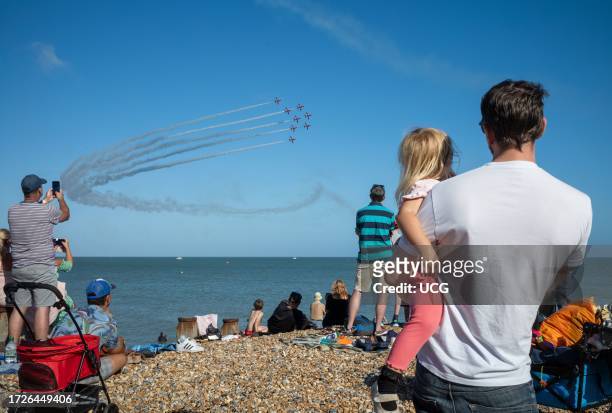 Family watches from Eastbourne beach as the world famous RAF display team The Red Arrows fly past the seafront at the annual Eastbourne Airbourne, an...