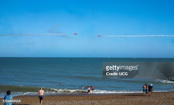People swim in the sea as the world famous RAF display team The Red Arrows perform along the seafront at the annual Eastbourne Airbourne, an...