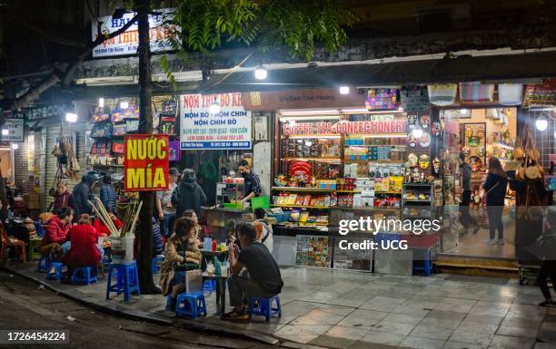 Vietnamese people sit at a pavement cafe at nighttime to drink sugarcane juice in central Hanoi, Vietnam.