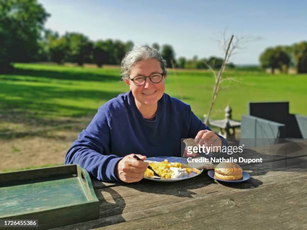 smiling woman eating on an outdoor terrace in the countryside - belgium countryside stock pictures, royalty-free photos & images