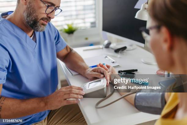 doctor measuring a patient's blood pressure. - low risk stock pictures, royalty-free photos & images