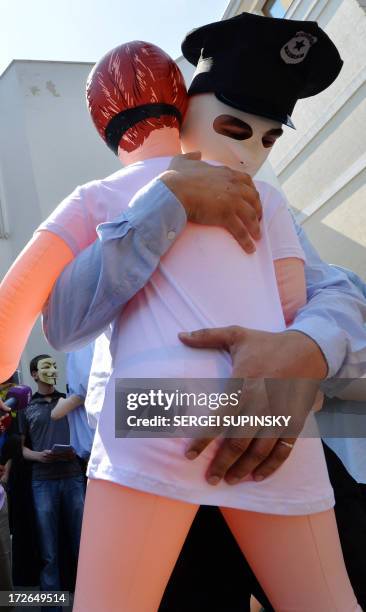 An activist dressed as a policeman from the public initiative "The movement of Guy Fawkes" dances with an inflatable doll for adults in front of the...