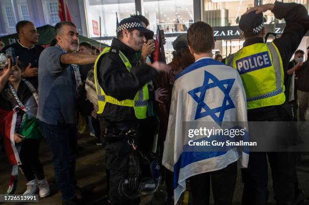 Couple of counter protestors with an Israeli flag are moved on by police as thousands of pro Palestine demonstrators protest at Israeli Embassy on...