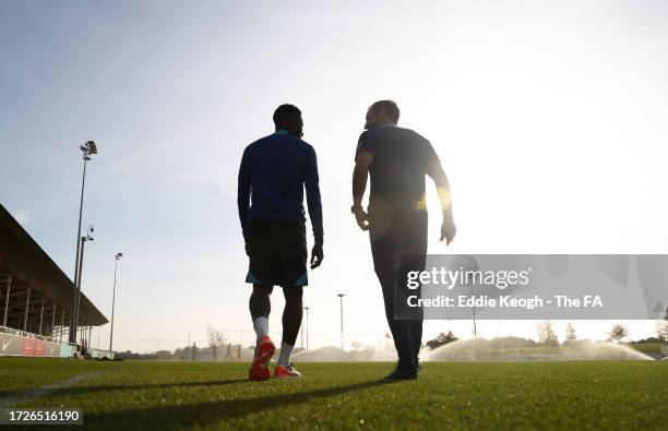 Gareth Southgate, Manager of England, and Eddie Nketiah of England talk as they walk out to a training session at St George's Park on October 09,...