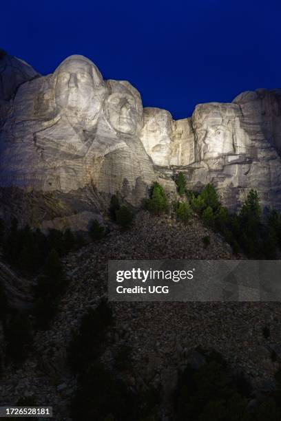 Carved granite busts of George Washington, Thomas Jefferson, Theodore "Teddy" Roosevelt and Abraham Lincoln framed by trees at Mount Rushmore...