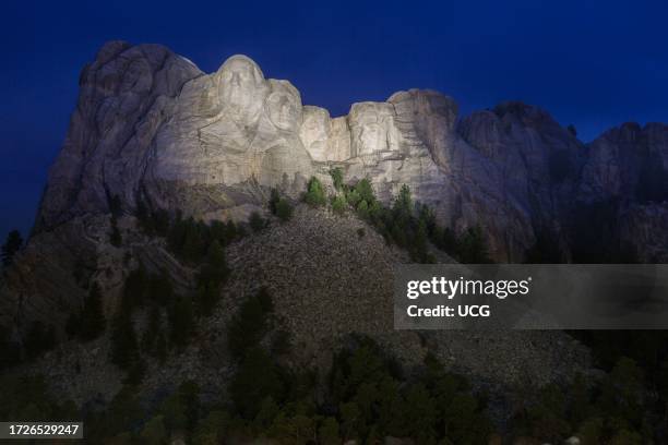 Carved granite busts of George Washington, Thomas Jefferson, Theodore "Teddy" Roosevelt and Abraham Lincoln framed by trees at Mount Rushmore...