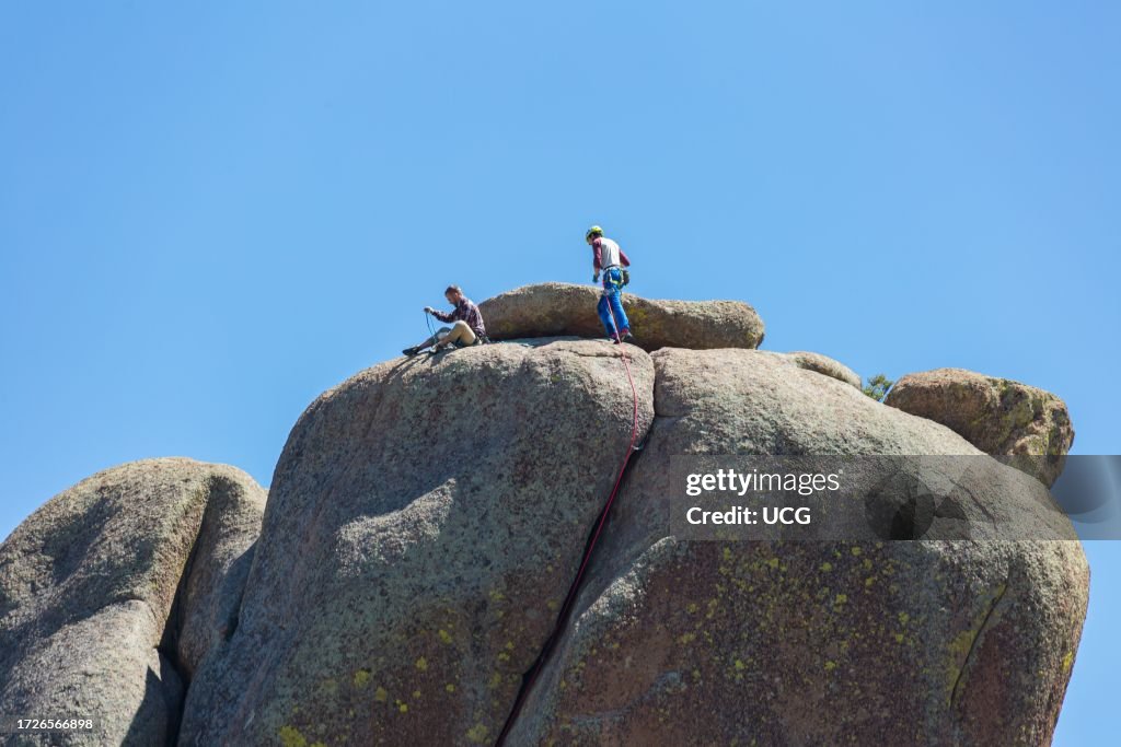 Two men rock climbing on a large granite boulder in the Vedauwoo Recreation Area of Medicine Bow National Forest in Wyoming