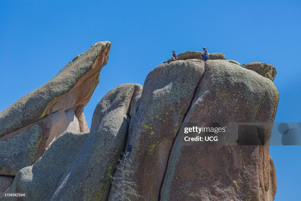 Men rock climbing on a large granite boulder in the Vedauwoo Recreation Area of Medicine Bow National Forest in Wyoming
