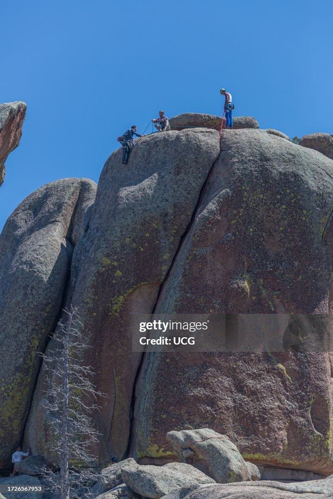 Men rock climbing on a large granite boulder in the Vedauwoo Recreation Area of Medicine Bow National Forest in Wyoming