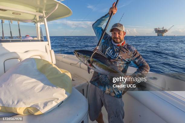 Offshore fisherman showing off his tuna caught near petroleum drilling rigs in the Gulf of Mexico.