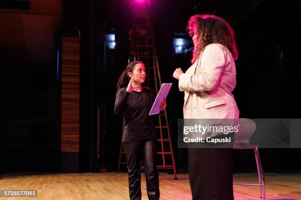 mitarbeiter geben einer frau auf der bühne anweisungen - bühnenbild stock-fotos und bilder