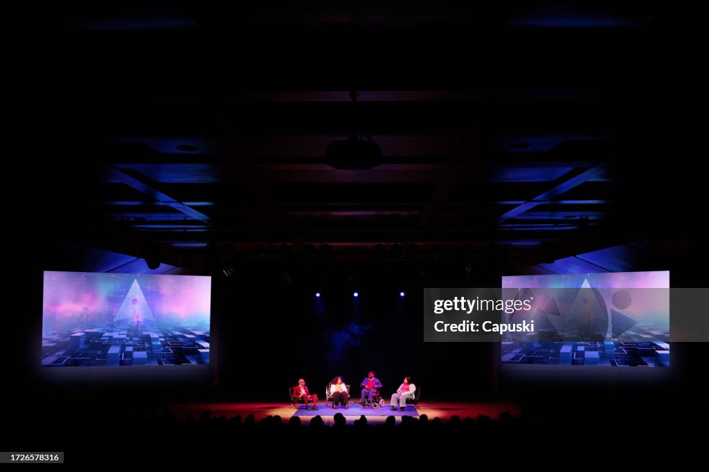 Group of people sitting on a stage giving a speech to an audience
