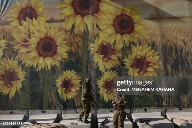 Israeli troops stand in front of a mural painting near kibbutz Nahal Oz on the border with the Gaza Strip on October 15, 2023. More than one million...