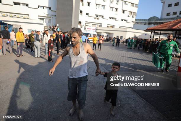 An injured Palestinian man and boy arrive to Al-Shifa hospital in Gaza City following Israeli bombardment on October 15, 2023. Israeli strikes on the...