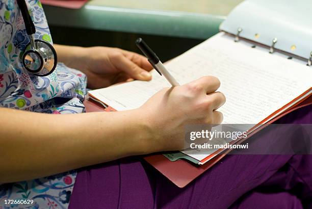 registered nurse charting on patient chart - nurse charting stock pictures, royalty-free photos & images