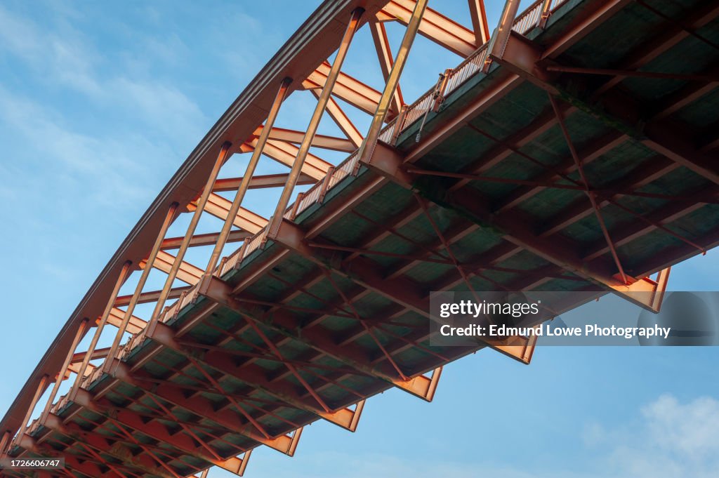 Detail of a red metal bridge against a lovely blue sky.