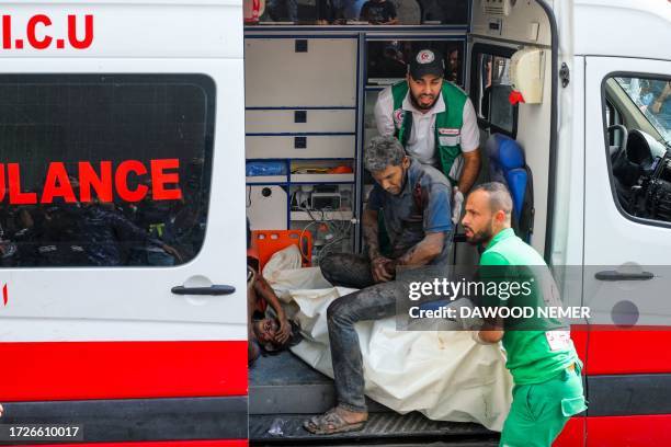Medics transport injured Palestinians into Al-Shifa hospital in Gaza City following Israeli bombardment on October 15, 2023. Israeli strikes on the...