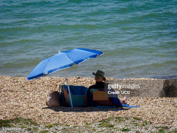 Man sat on the beach at Lee-on-the-Solent, Hampshire, UK.