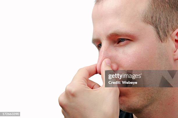 young man holding nose to signify a bad smell - pinching nose stockfoto's en -beelden