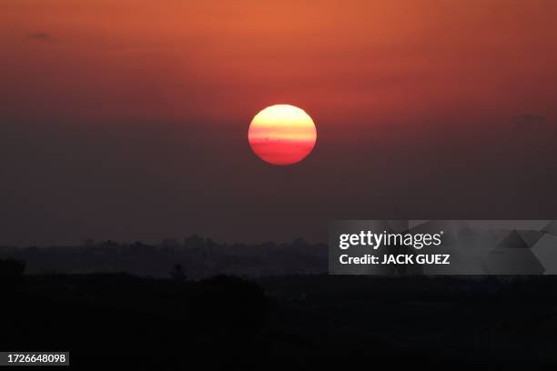 Picture taken from the southern Israeli side of the border with the Gaza Strip on October 15 shows the setting sun above the Palestinian enclave. In...