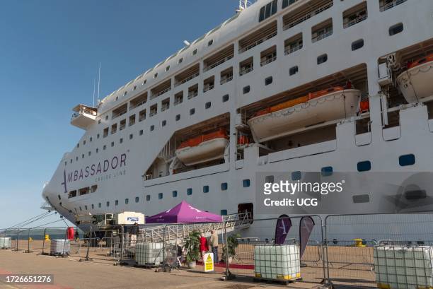 Invergordon, Scotland, UK, Cromarty Firth port security fence and cruise ship alongside with welcome tent for disembarking passengers against a blue...