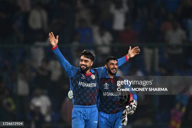 Afghanistan's Rashid Khan celebrates with teammate after taking the wicket of England's Mark Wood during the 2023 ICC Men's Cricket World Cup one-day...